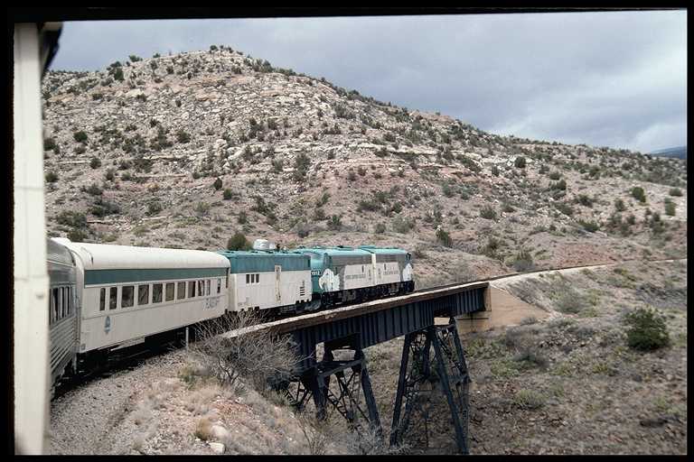 Passenger train crossing steel trestle along Verde River.