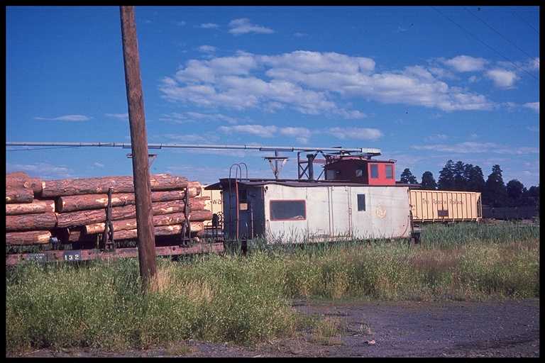 Apache RR caboose at rear of log train.