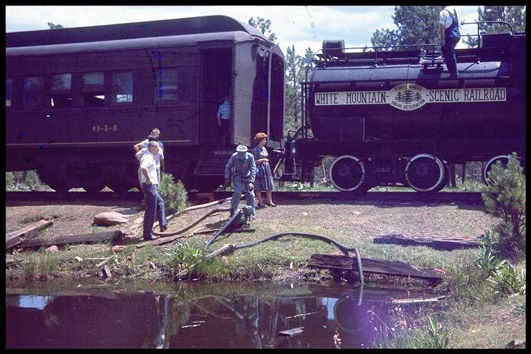 Filling tender of steam engine from pond near the track.
